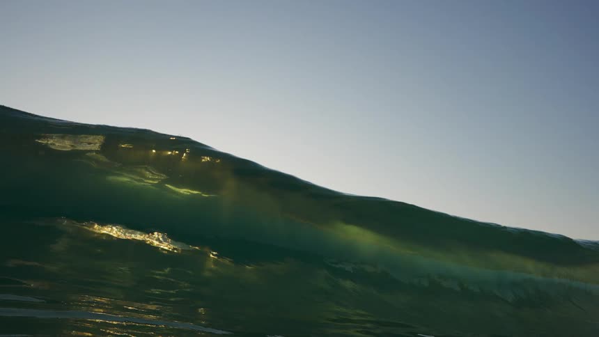 Ocean wave breaks against the beach at dusk