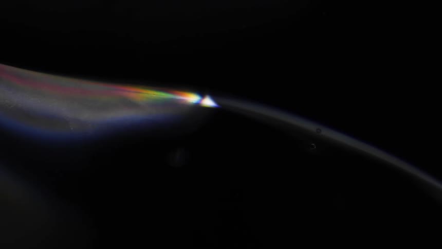 Colorful light spreads across curving surface contrasting with black