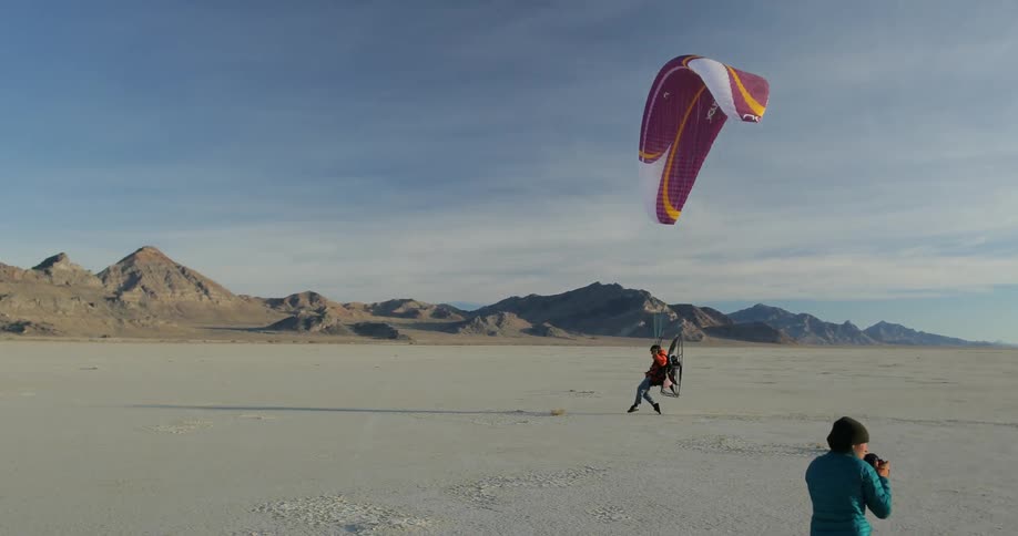 A photographer takes pictures of a motorized hang-glider landing