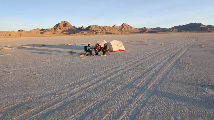 People are sitting near tents in a flat area