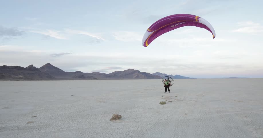 A person lands while parachuting in the desert