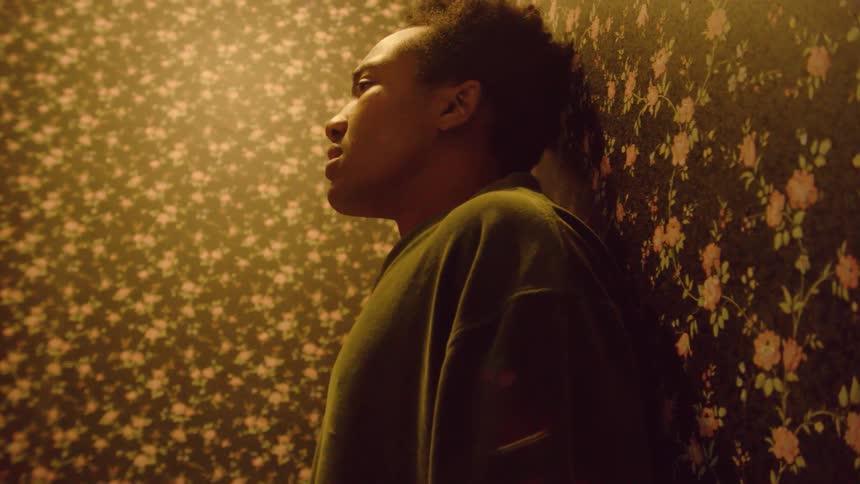Young man standing in a room up against the wall taking deep breaths