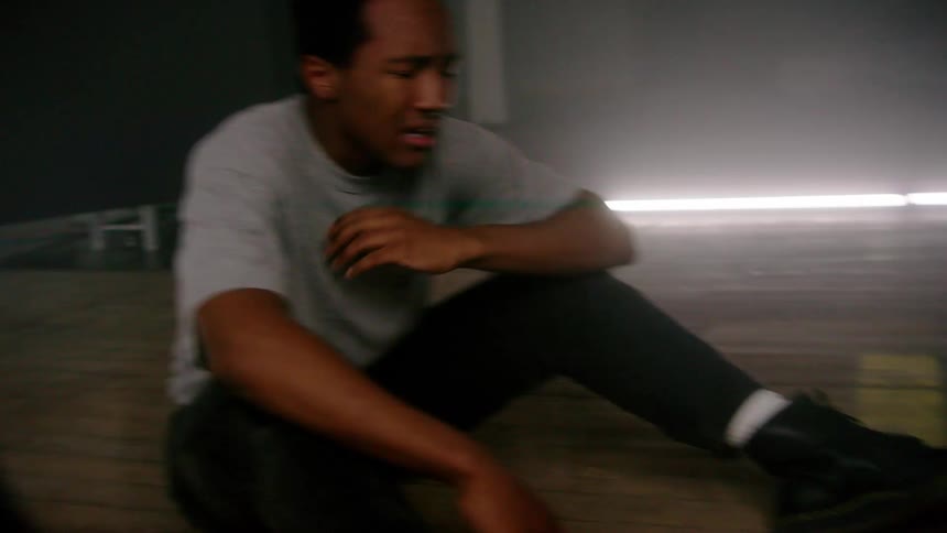 Young man sitting on the floor in a room with strobing lights breathing rapidly and crying