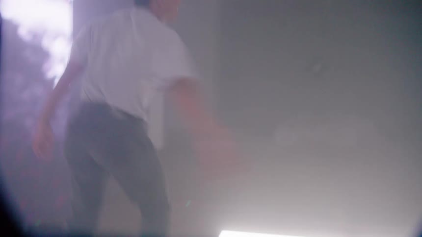 Man jumps back and forth in large building between two large flickering screens