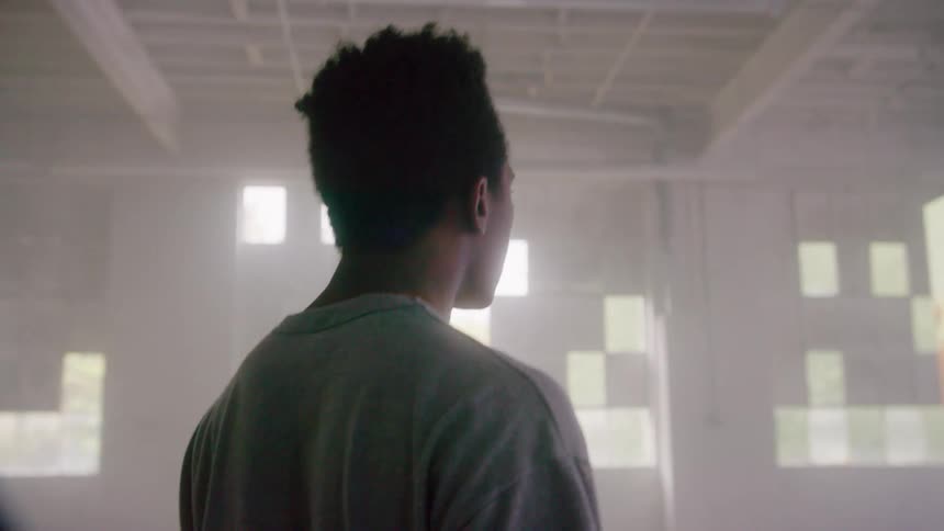 A young male walks through a large warehouse filled with large digital display screens
