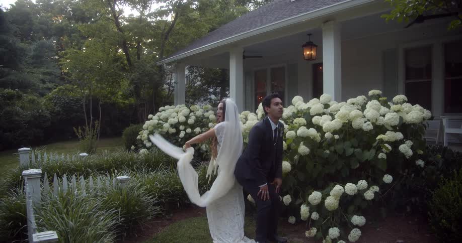A newly married bride and groom dance playfully in a garden
