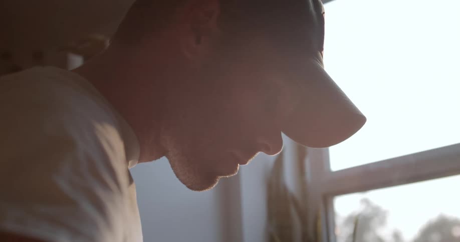 Smoke rises up as a man in a baseball cap cooks in his kitchen
