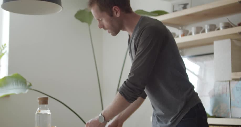 A white man is standing in a well lit office and organizing photographs on his desk
