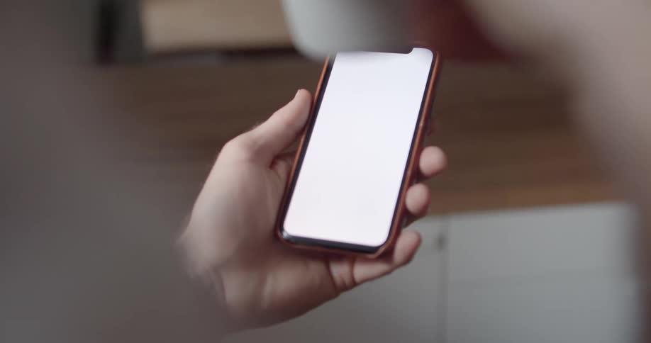 A man holds his smart phone while taking a sip from his coffee mug