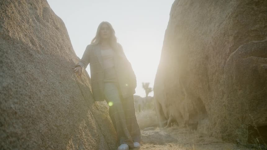 A female caucasian standing outside between two large boulders
