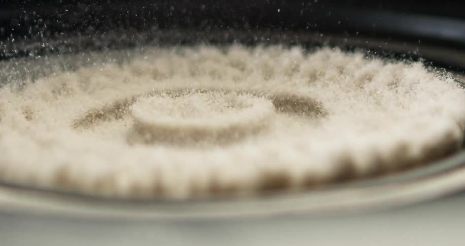 White granules moving and vibrating on black surface