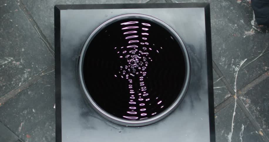 A circular screen sits on a marble floor and flashes a digital display made of the number zero