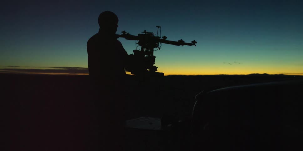 Man inspecting a drone at sunset