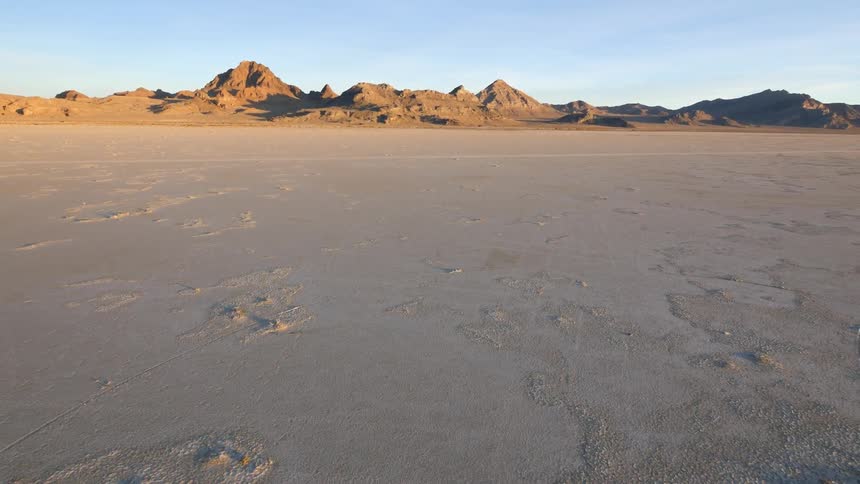 A flat desert with mountains in the distance