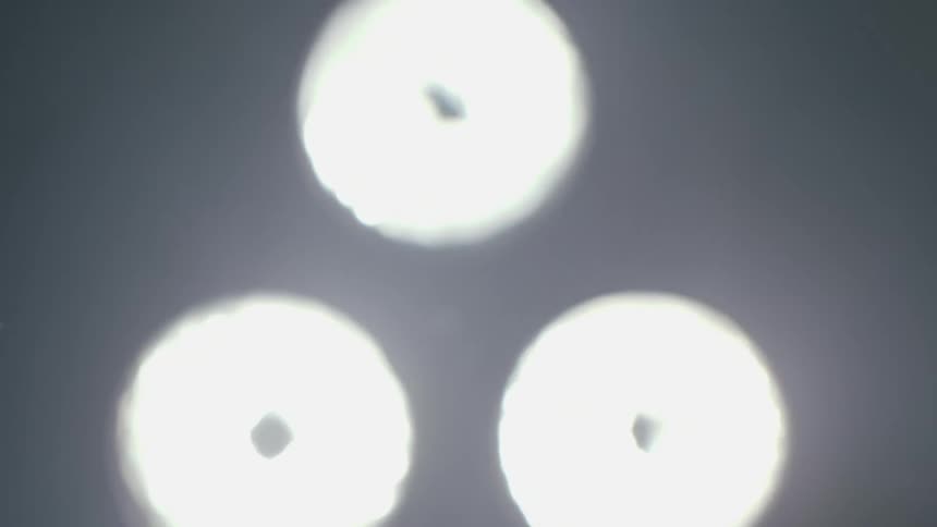 Out of focus close up of a surgical lighting lamp flashing on and off in a dimly lit room