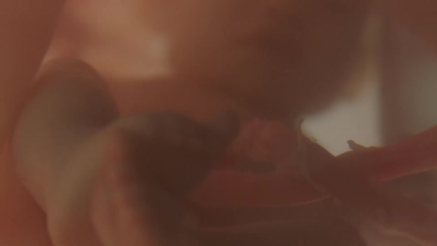 A baby floating in liquid with intermittent light