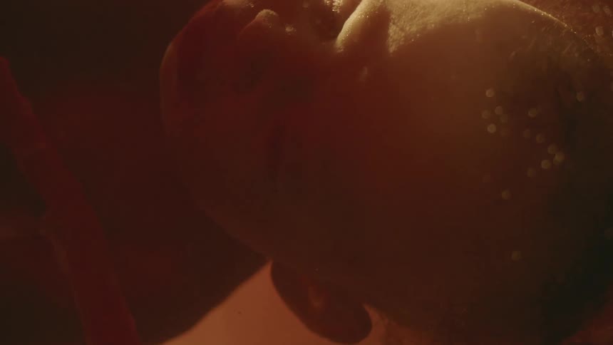 A babys face and head with an umbilical cord with lights cascading