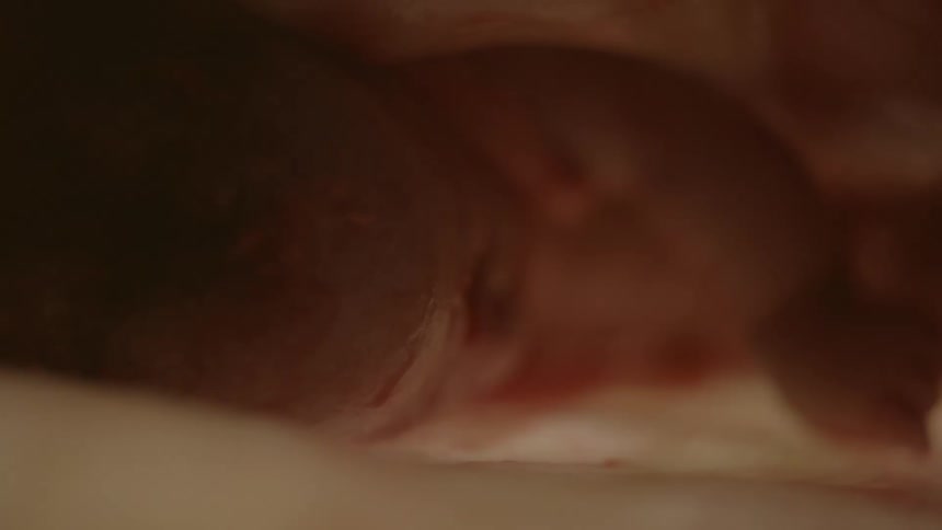 A babys profile fist and arm are visible against a white surface