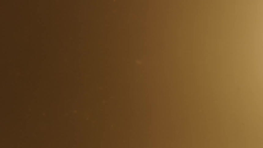 Particles float in cloudy pale brown orange liquid