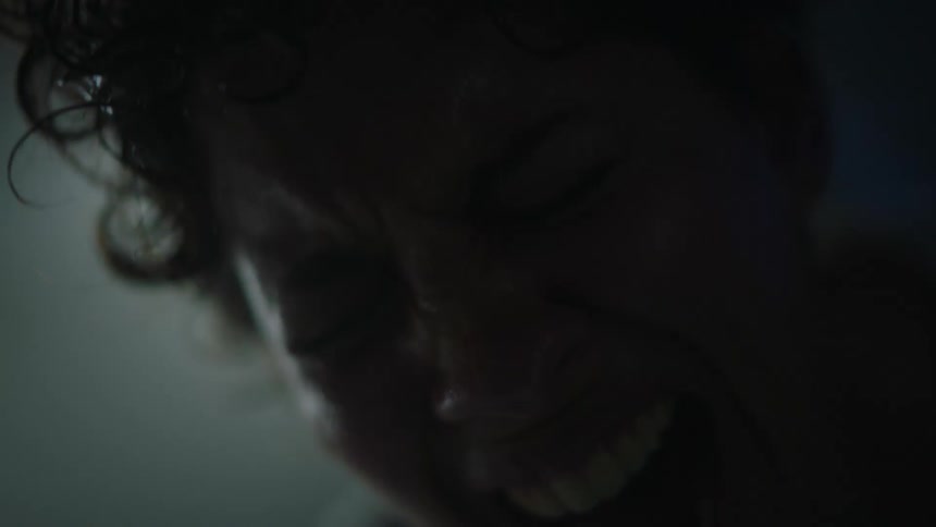 Close up of the face of a woman in labor pains in a dimly lit hospital room