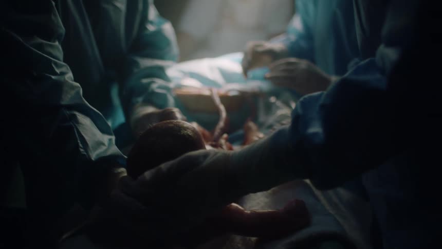 Medical staff lie a newborn baby down as they work on it