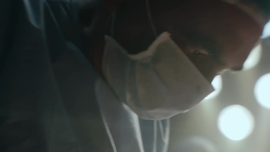 A baby was just born in an operating room with a doctor working on him or her and the mother