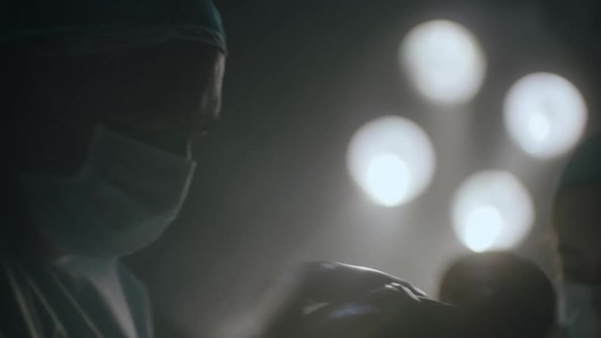 A doctor removes a newborn from the mother in the operating room of a hospital