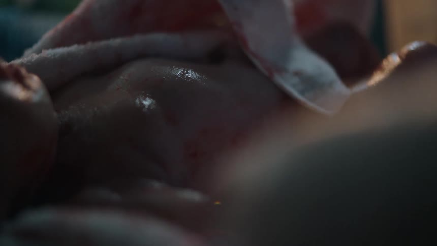 A newborn is lying on its back and the blanket is removed from the front of the baby