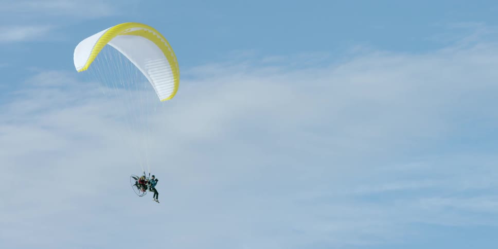 People gliding through the air with a paramotor