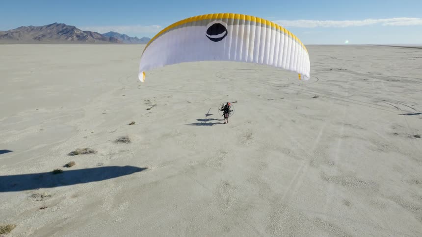 A motorized hang glider takes off on a sunny day