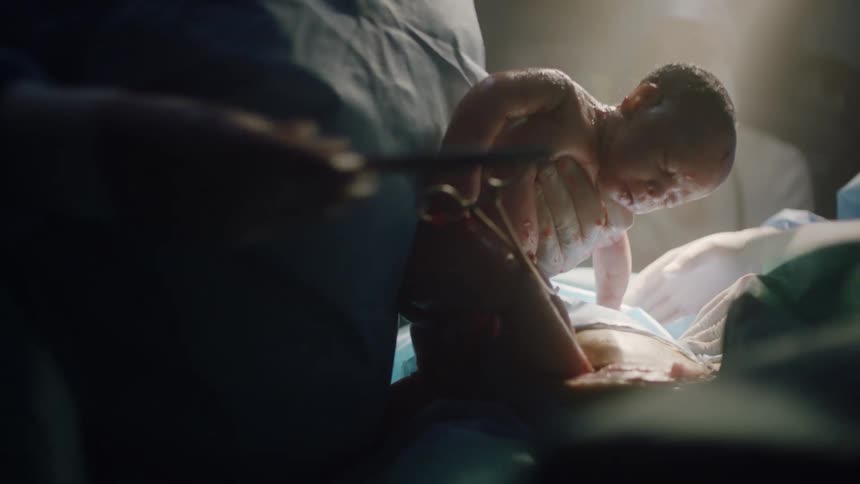 A team of medical professionals tend to a newborn baby in the delivery room