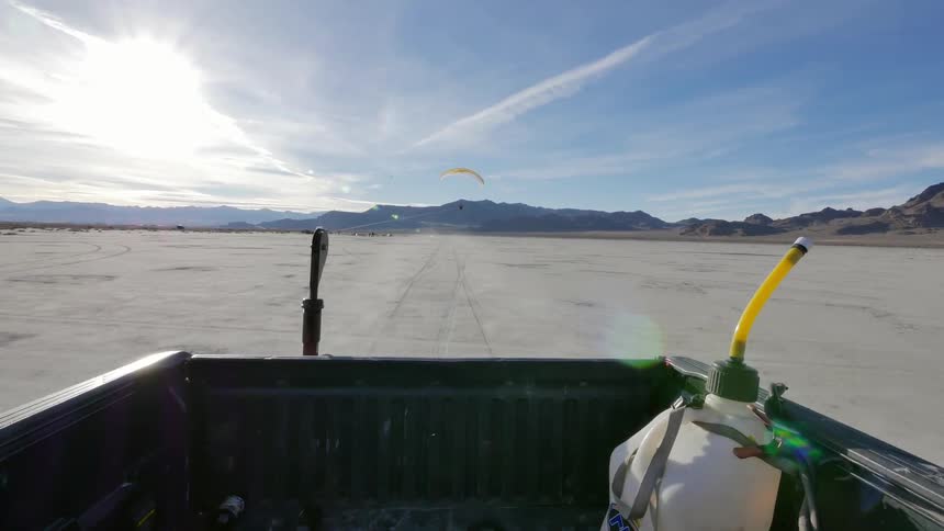 View from the back of a pickup as it drives over a desert