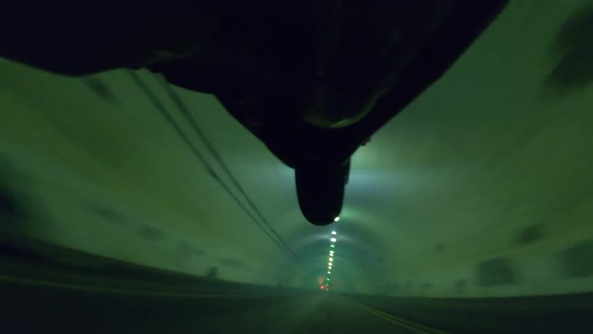 A motorcycle wheel lifts off the road as it drives through a tunnel