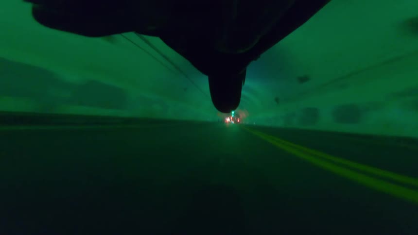 A motorcycle driving in a tunnel lifts up on to one wheel