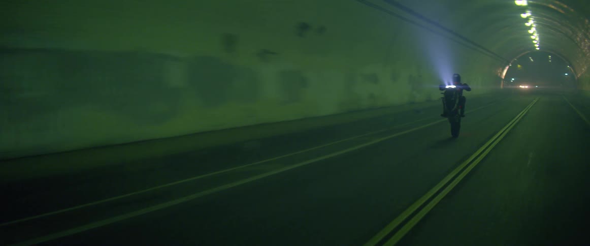 A person is driving a motorcycle through a tunnel at night
