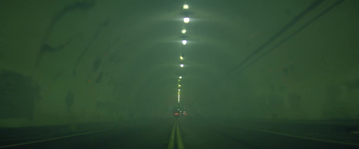 A person drives a motorcycle through a misty tunnel