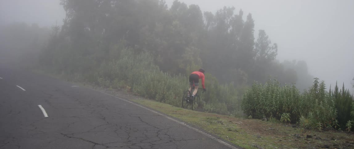 cyclist traversing from up hill asphalt road onto downhill dirt road