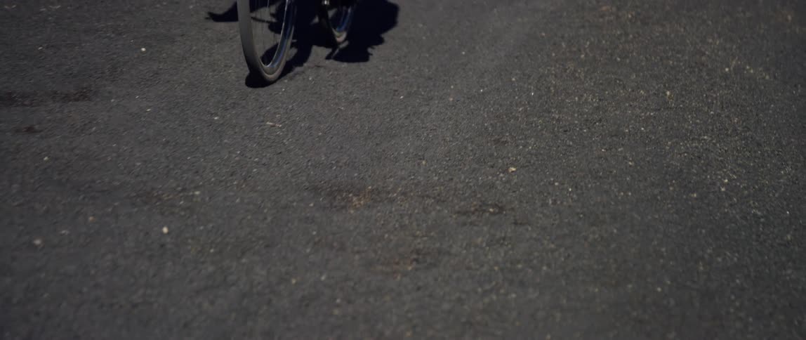 tracking shot of dirt road passing by with a cyclist in the background