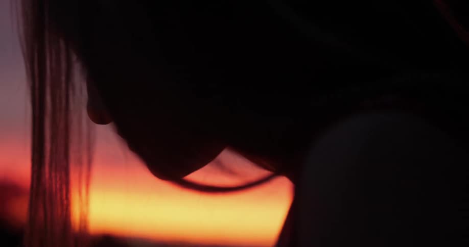 Dark silhouette of a long haired womans head at sunset