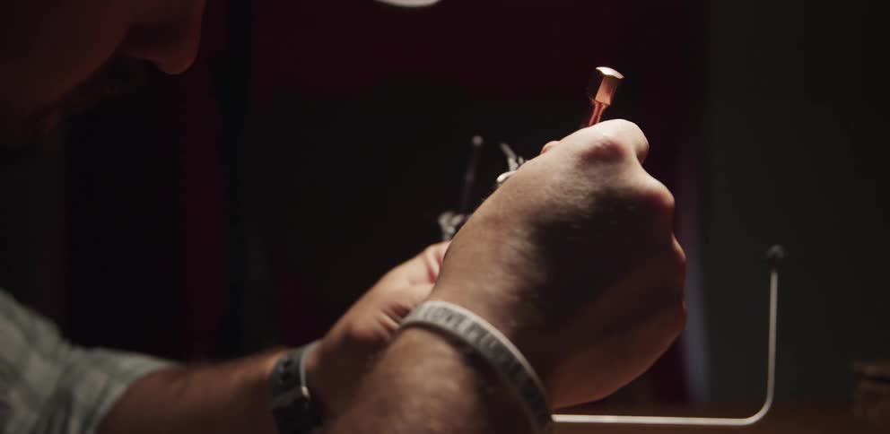A man concentrates as he uses a small tool