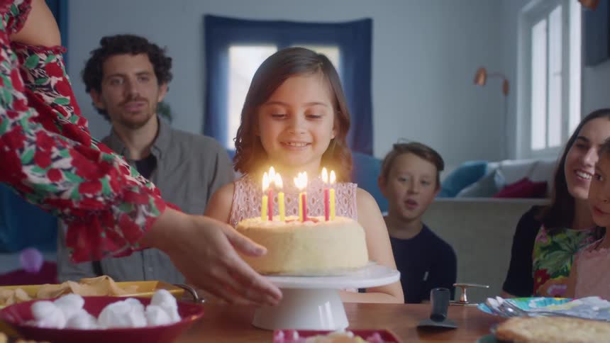 Family and friends celebrate a little girls birthday with birthday cake and candles