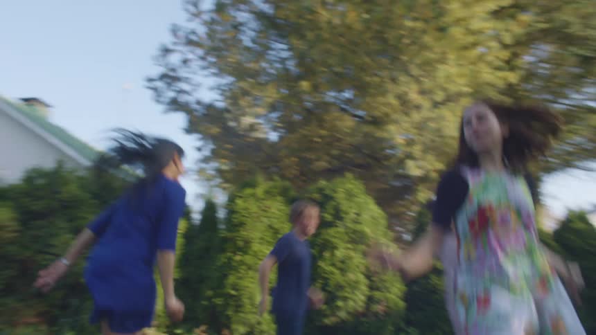 A group of kids jump on a trampoline in a backyard