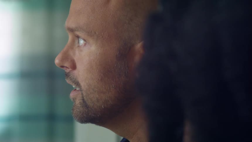 Young bald man talking to friends in a room at home