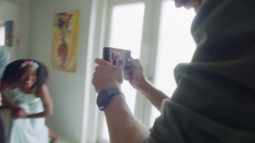 A man holds a cell phone taking a photo of a group of men and women with also a baby