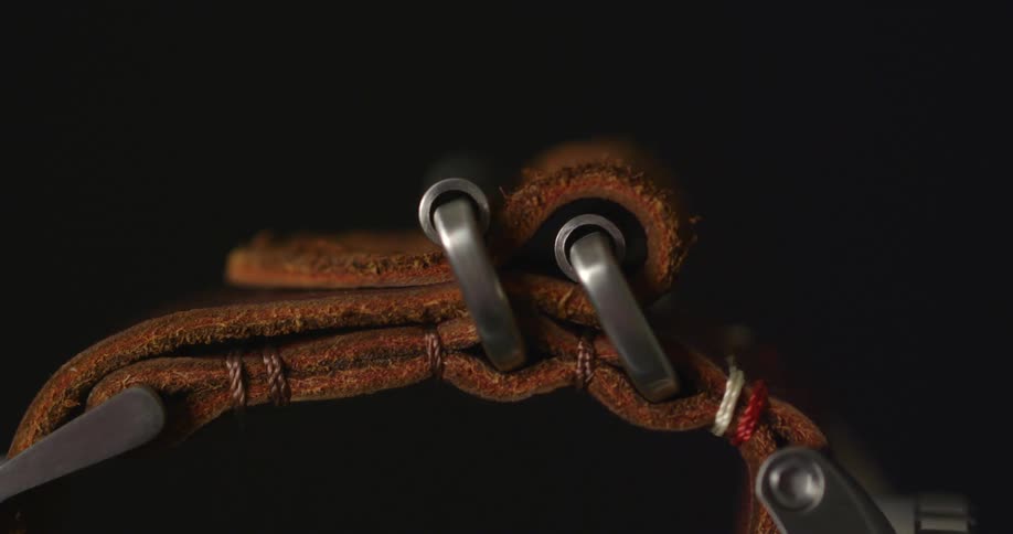 A silver metal watch with a rugged brown leather strap spins around
