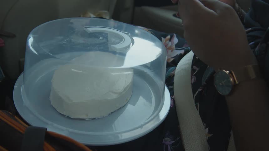 A woman sits in a car with a dessert in her lap
