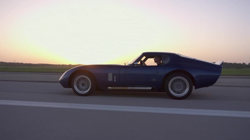 A car is driving on a road at dusk