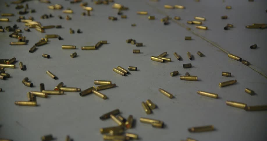 Hundreds of gold bullets and shell casings litter the ground at a gun range