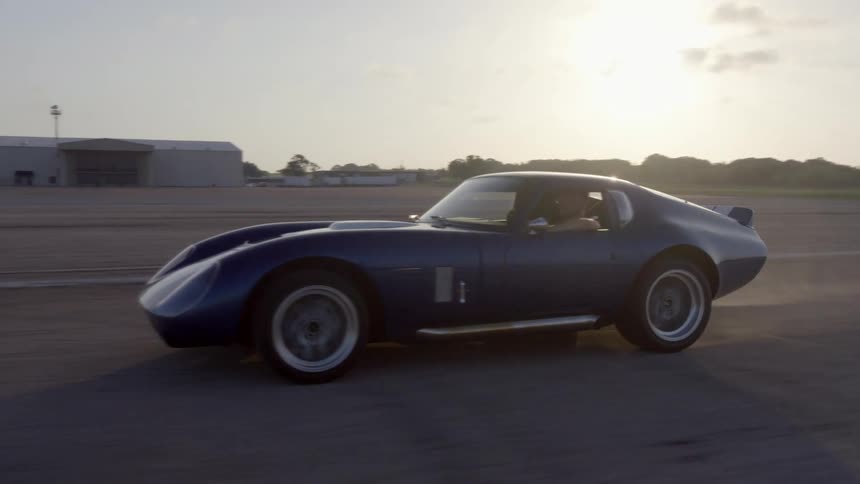 A man is driving a car outdoors at dusk