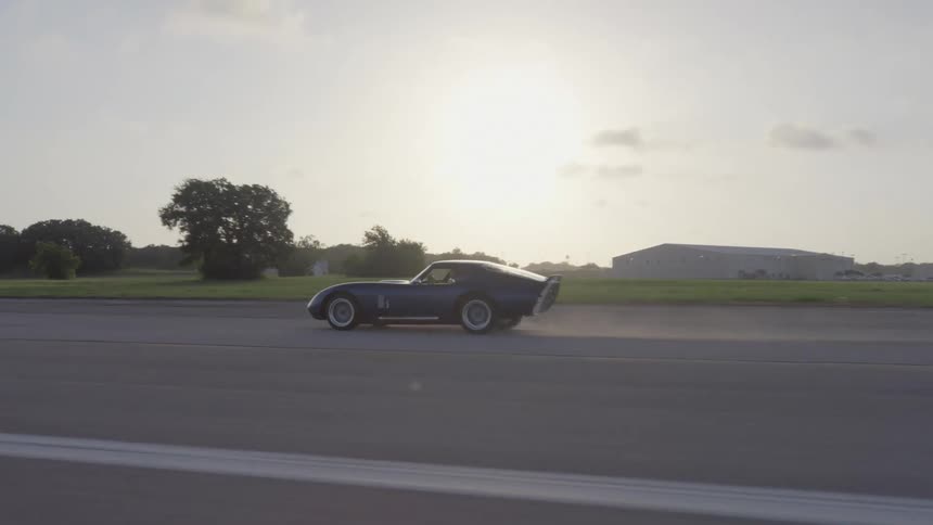 A sports car speeds along a rural race track